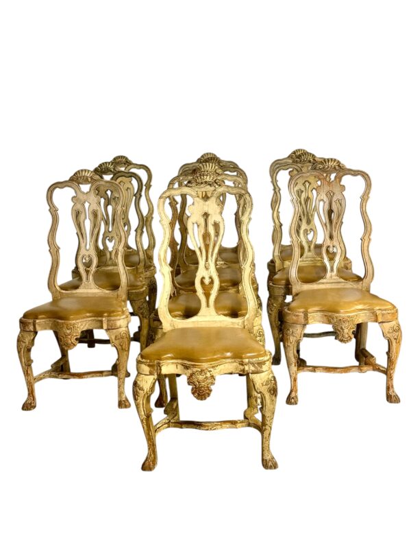 An exceptional and rare set of 10 Italian Rococo dining chairs, crafted in solid beechwood and dating from the late 18th to early 19th century. These chairs feature an elegant hand-carved silhouette with serpentine lines and pierced backs, adorned with classic Rococo motifs such as acanthus scrolls, shell crests, and foliate carvings. The original polychrome and gilt finish, now beautifully distressed, reveals layers of age and patina that only time can create, adding depth and authenticity to each piece. The seats are upholstered in rich tan leather with a subtly aged sheen that harmonizes perfectly with the worn gilding. Standing on carved cabriole legs terminating in paw feet, each chair is detailed with stylized floral and scroll ornaments, including a central cartouche on the seat rail. The overall design is both dramatic and refined, offering a sense of grandeur without being overly ornate. Likely originating from Northern Italy, these chairs were designed for an aristocratic interior, combining decorative artistry with comfort and durability. Their scale and unified design make them ideal for a statement dining room, a refined formal setting, or a historic design project.